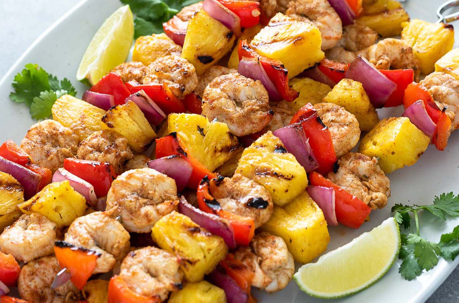 skewers of shrimp, pineapple, bell pepper, onion, with lime wedge