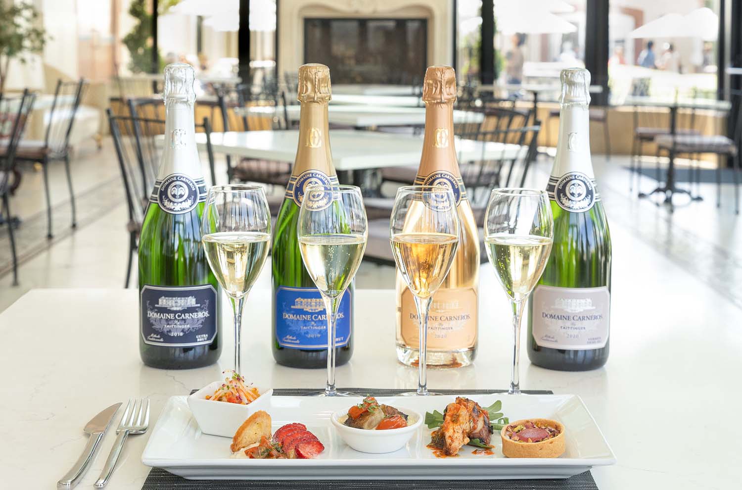 four sparkling flutes with plate of five bites