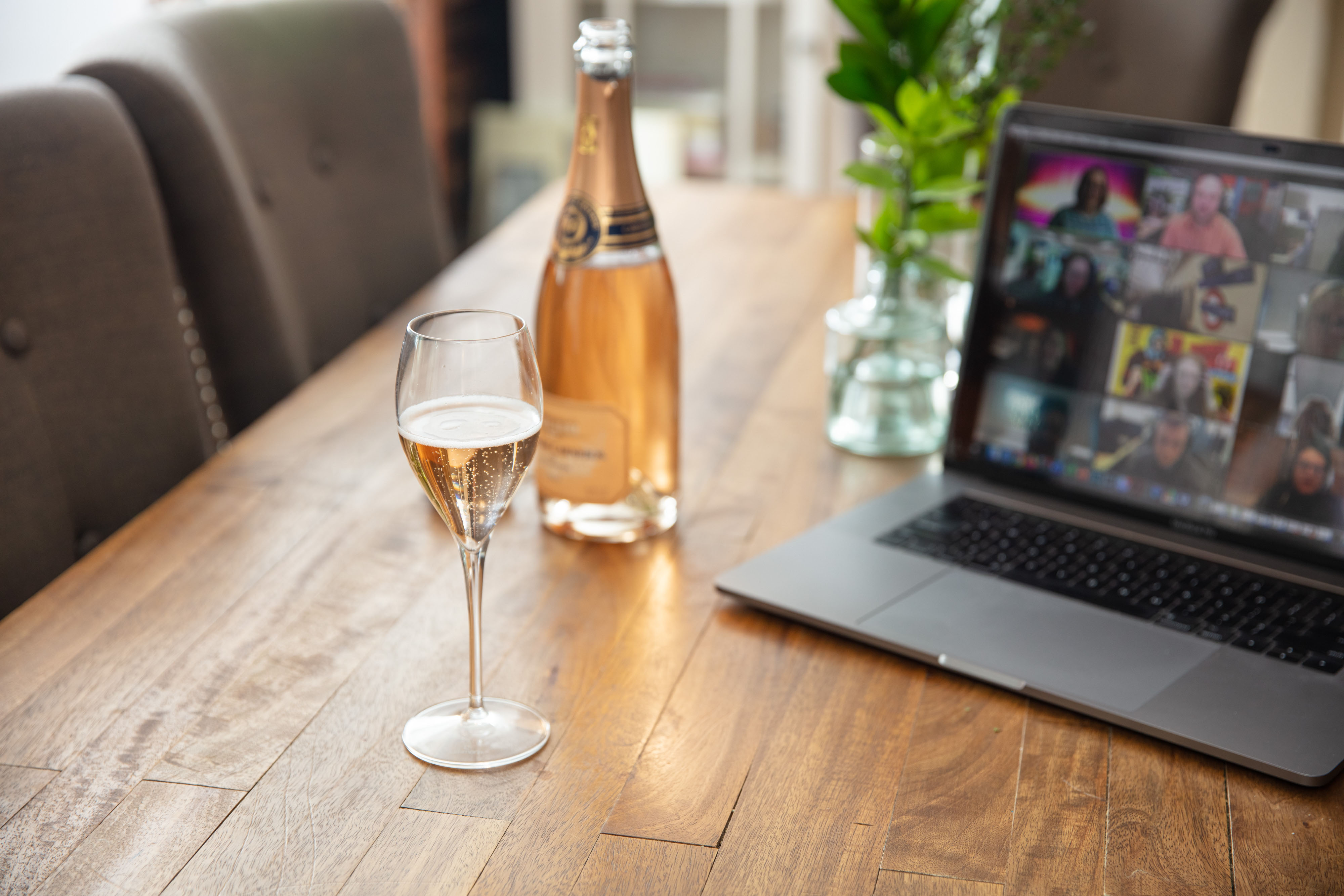bottle of wine in front of computer with zoom conference on screen