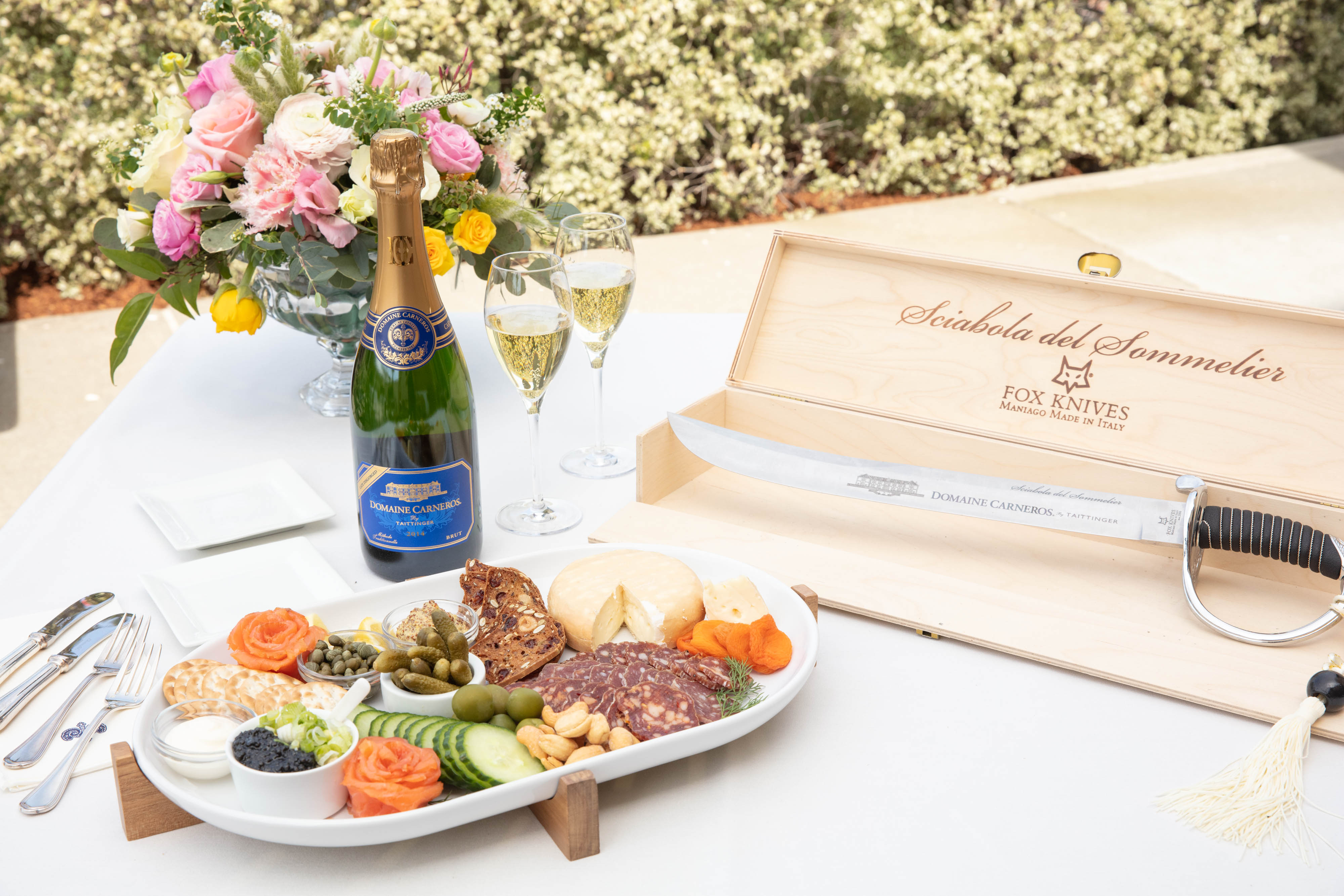 the food pairing plate with a bottle of sparkling wine, two glasses and a saber