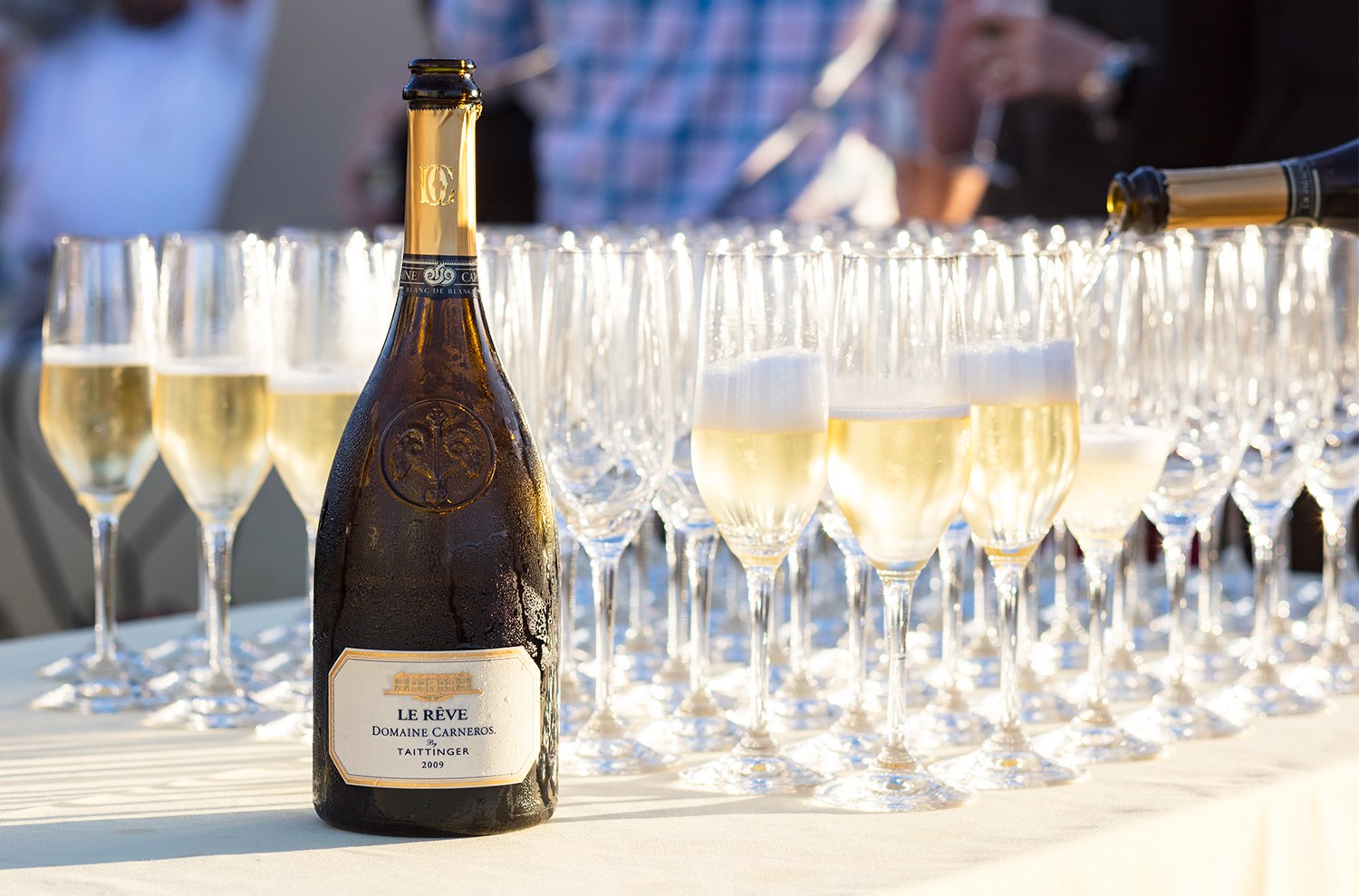 Bottle of Le Reve with sparkling wine flutes and Chateau in background