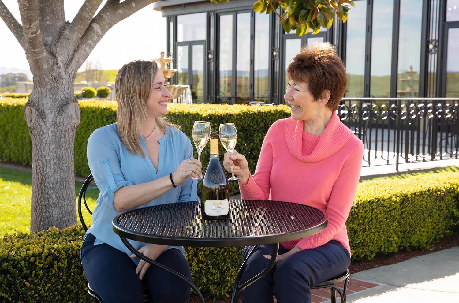 CEO Remi and founding winemaker Eileen seated at a table with a bottle of Le Reve and two glasses of sparkling wine