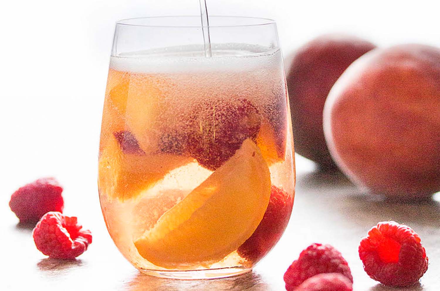 Glass of sparkling sangria with raspberries and peaches