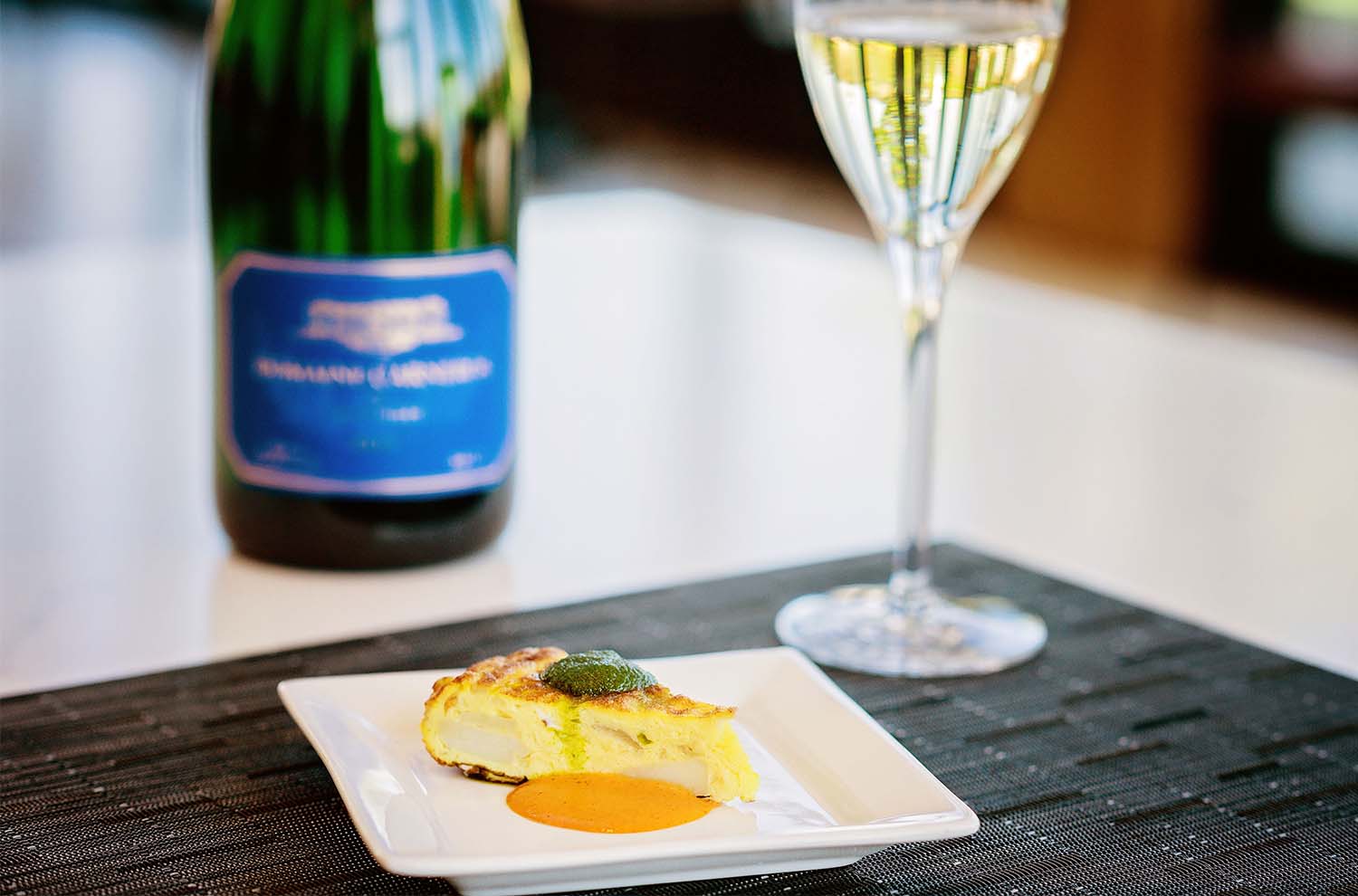 Tortilla Espanola on plate with glass of wine and bottle in background