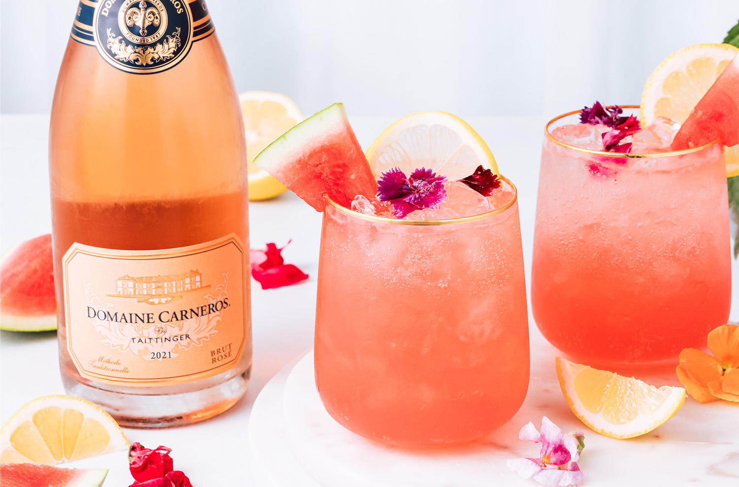 two glasses of watermelon cocktail with rose bottle